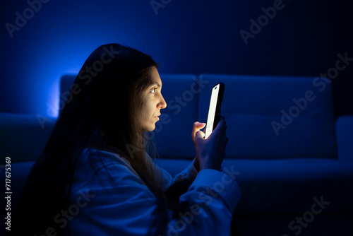A young person appears to be having an eye problem in a poorly lit room, suggesting the stress of poor eyesight when viewing devices at a close distance.