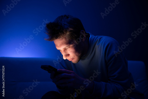 A young person appears to be having an eye problem in a poorly lit room, suggesting the stress of poor eyesight when viewing devices at a close distance.
