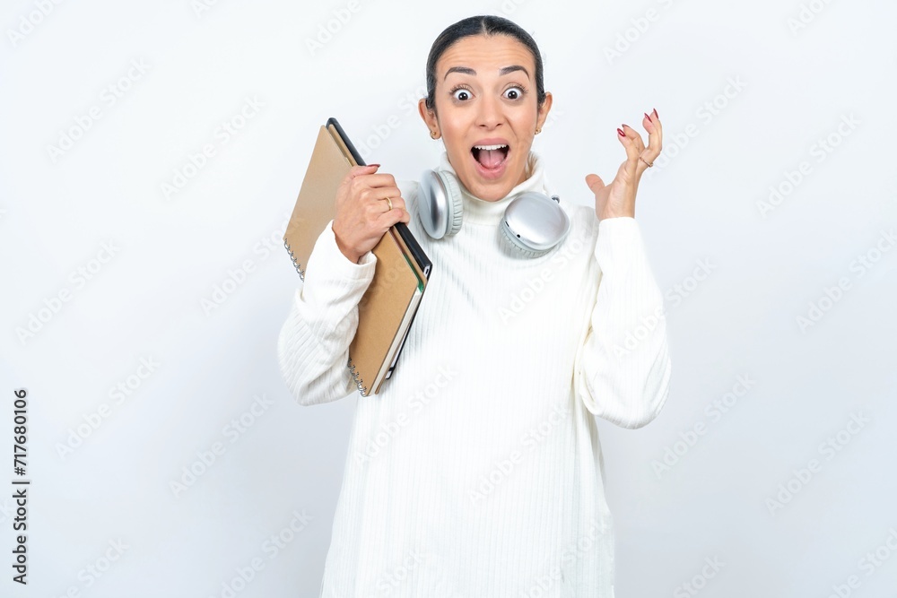 Surprised happy Young beautiful woman wearing white turtleneck sweater, glad to see big discounts on clothes, expresses shock, keeps hands near head, jaw dropped. Surprised happy Young beautiful woman wearing white turtleneck sweater, glad to see big discounts on clothes, expresses shock, keeps hands near head, jaw dropped.