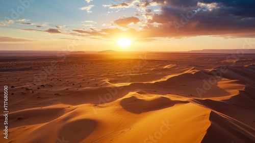 Aerial shot of an expansive desert with sand dunes at sunrise background.