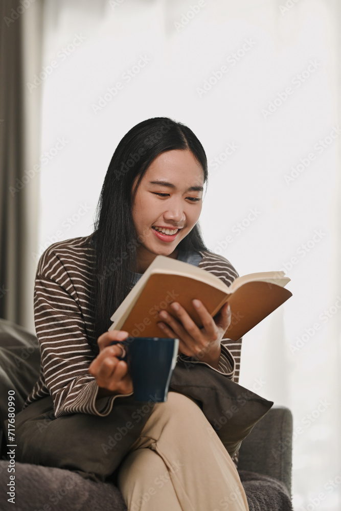 Relaxed young woman in casual clothes reading book, spending free time at home on weekend Relaxed young woman in casual clothes reading book, spending free time at home on weekend