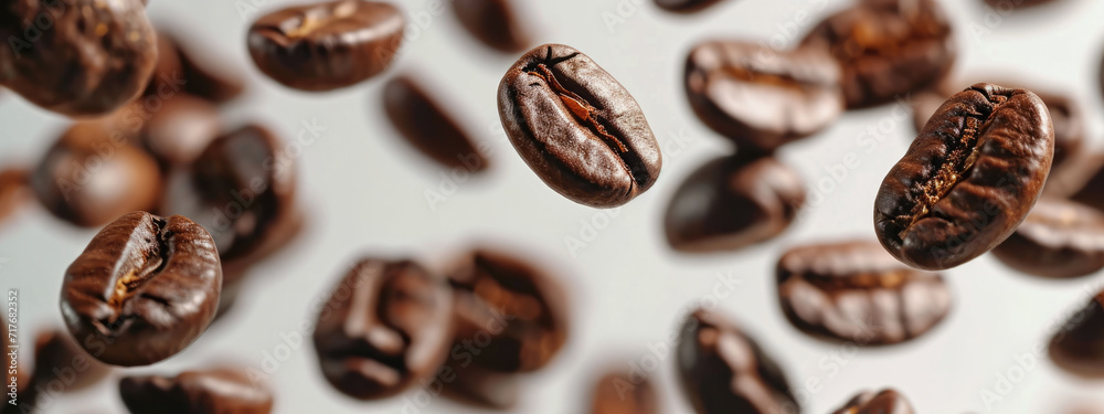 Close-up of scattered roasted coffee beans on a white background, with a central bean in sharp focus.