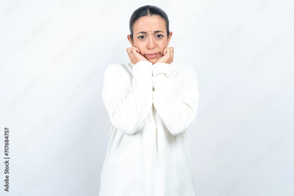 Portrait of sad Young beautiful woman wearing white turtleneck sweater hands face Portrait of sad Young beautiful woman wearing white turtleneck sweater hands face