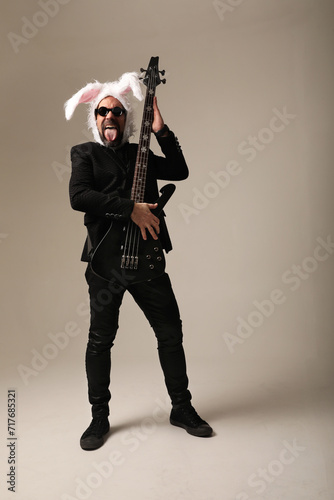 Rock musician wearing bunny ears on his head with electric guitar at the studio. © face_reader_img