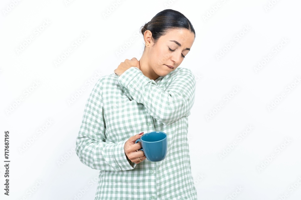 Beautiful young woman wearing green plaid pyjama and holding a cup got back pain Beautiful young woman wearing green plaid pyjama and holding a cup got back pain