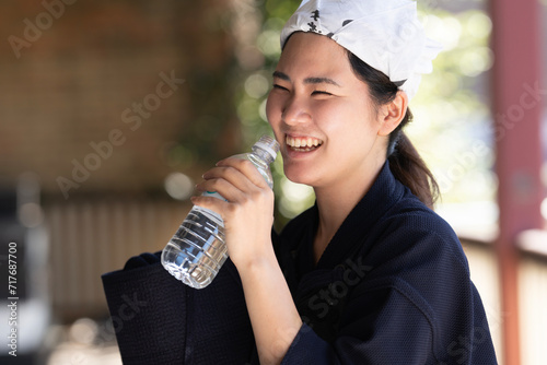 剣道の道着姿で水のペットボトルを持って笑っている女性剣士