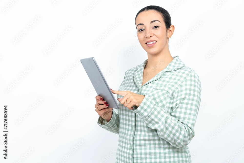 Photo of happy cheerful smart Beautiful young woman wearing green plaid pyjama and holding a cup hold tablet browsing internet Photo of happy cheerful smart Beautiful young woman wearing green plaid pyjama and holding a cup hold tablet browsing internet