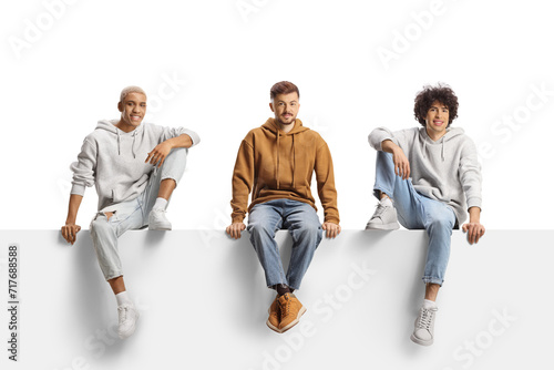 Young casual trendy men sitting on a blank panel
