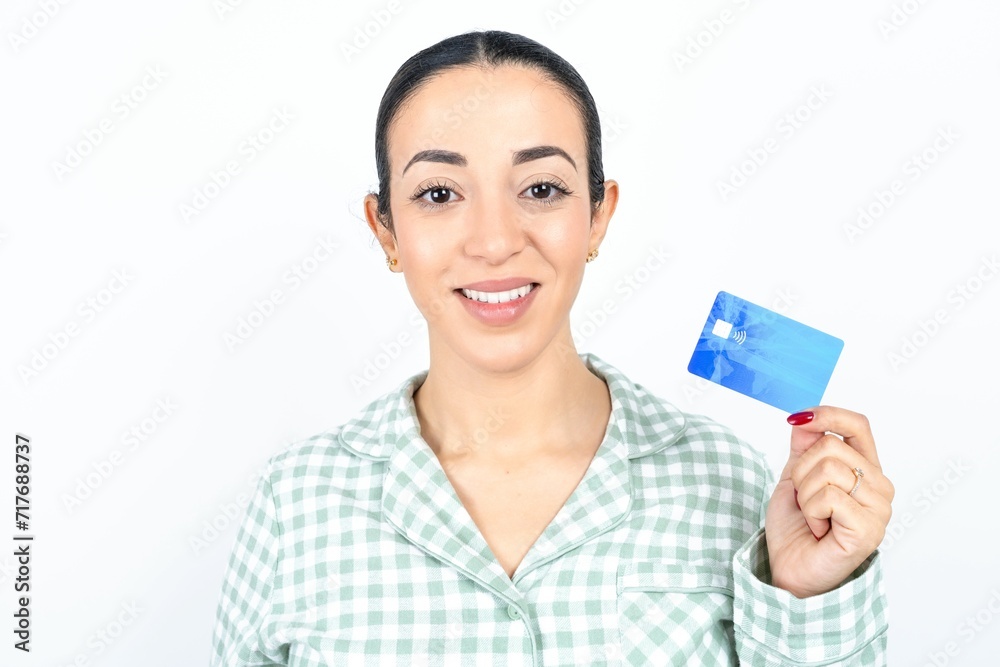 Photo of happy cheerful smiling positive Beautiful young woman wearing green plaid pyjama and holding a cup recommend credit card Photo of happy cheerful smiling positive Beautiful young woman wearing green plaid pyjama and holding a cup recommend credit card