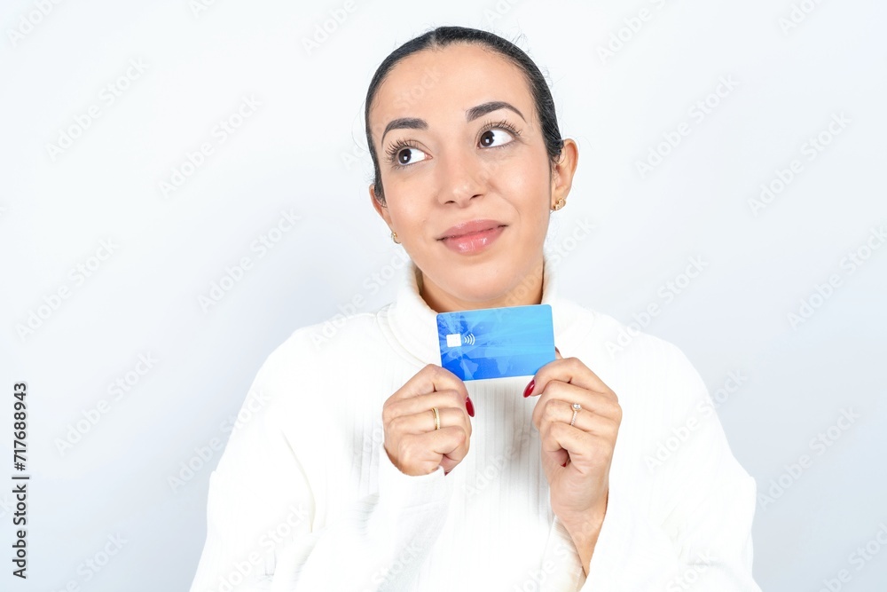 Photo of cheerful Young beautiful woman wearing white turtleneck sweater hold debit card look empty space Photo of cheerful Young beautiful woman wearing white turtleneck sweater hold debit card look empty space