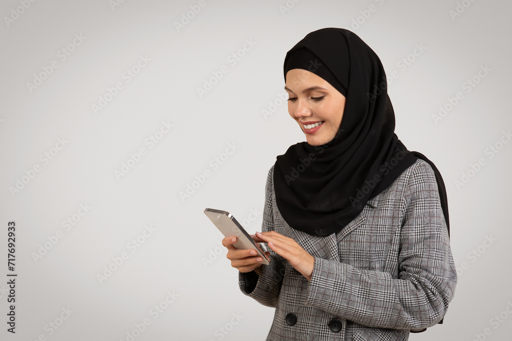 Engaged Muslim woman using smartphone and smiling Engaged Muslim woman using smartphone and smiling