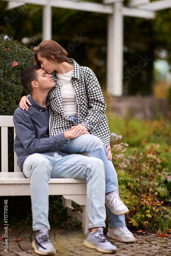 Autumn Romance: Young Couple Embracing and Kissing on Park Bench. Young couple kissing and rejoices at the lake. lovely young couple kissing outdoors in autumn. Embraced in Autumn's Warmth: Couple's © andreiko