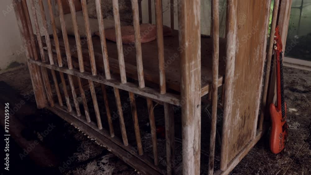 Film of long abandoned house - creepy - close up of old baby bed with a stuffed weathered bear toy - camera tilt up