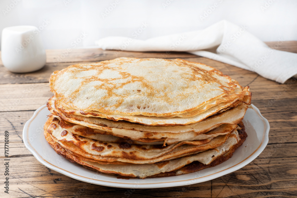 Thin pancakes on a plate, wooden background. The concept of a delicious breakfast or Maslenitsa