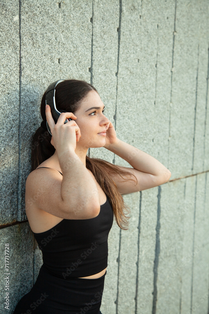 Chica deportista escuchando música con auriculares en el parque. Estilo de vida saludable. 