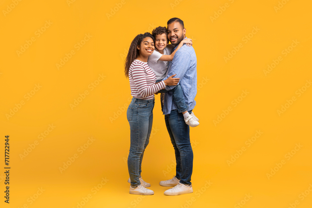 Happy black family with little son cuddling and smiling at camera Happy black family with little son cuddling and smiling at camera