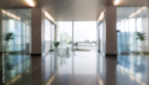 Blurred hotel or office building lobby blur background interior view toward reception hall, modern luxury white room space with blurry corridor and building glass wall window photo