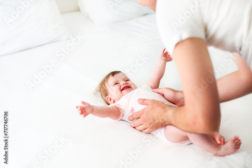 Six month baby on bed playing with father