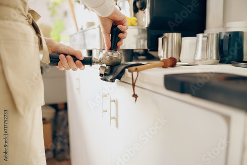 Close-up of barista using a tamper to press ground coffee into a portafilter at the coffee shop photo