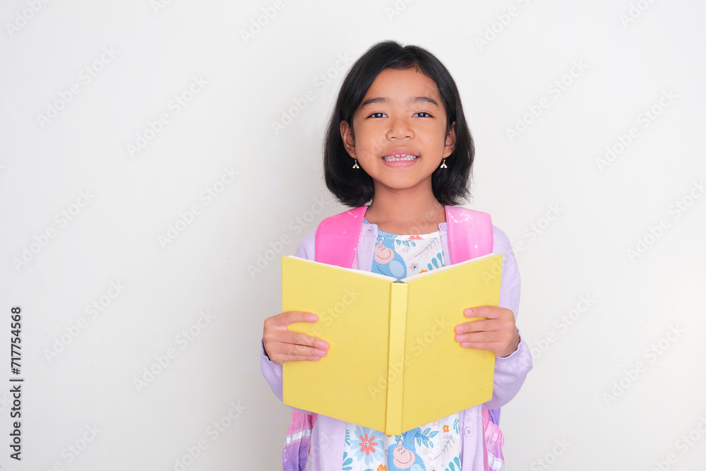 Asian kid smiling happy at the camera while holding a book Asian kid smiling happy at the camera while holding a book