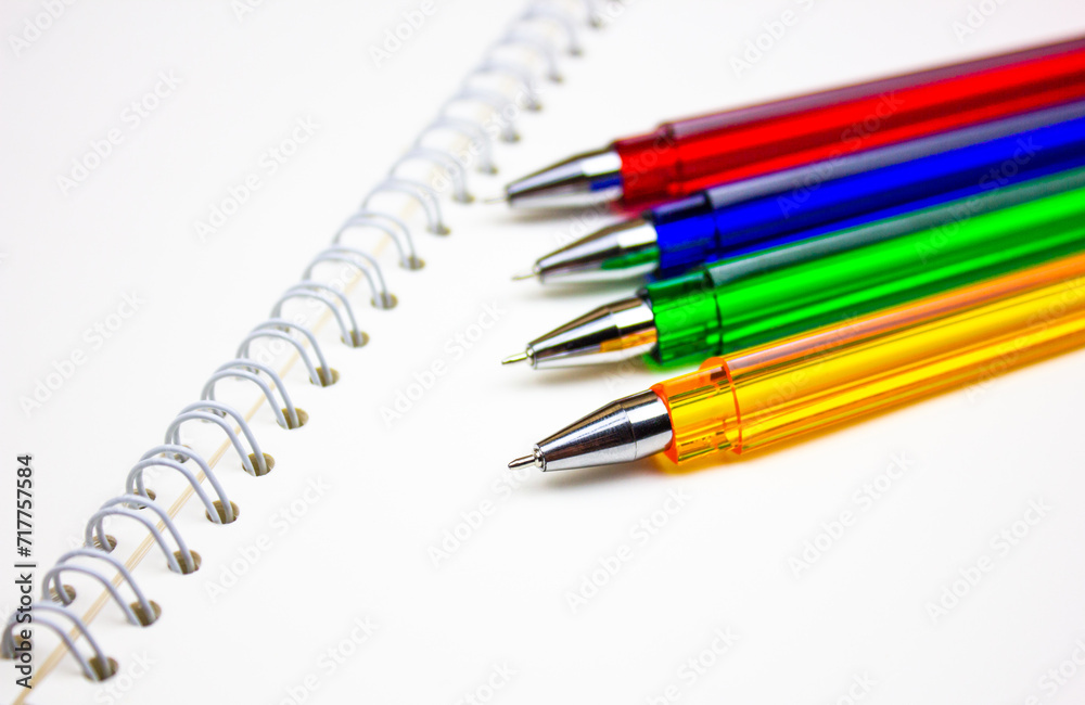 Ballpoint pens. Choice of handles. Colored pens. Ink pens for writing. Pens lie on the notepad page. Office stationery concept. Ballpoint pens. Choice of handles. Colored pens. Ink pens for writing. Pens lie on the notepad page. Office stationery concept.