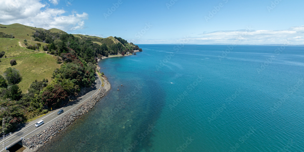 Aerial: Coastline road and flowering pohutukawa trees in Kerata, near Thames, Coromandel Peninsula, New Zealand.