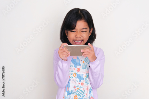 Asian kid showing furious face expression when playing with gadget photo