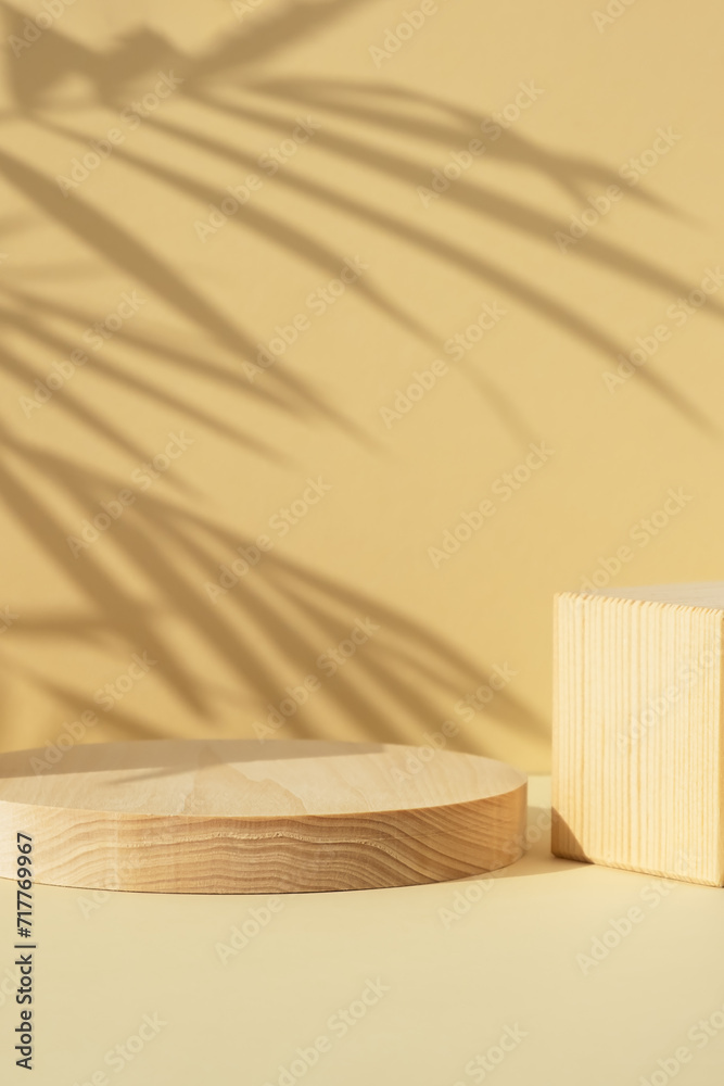 Wooden scenes of different geometric shapes with a shadow of tropical palm leaves on a beige background. Premium podium for advertising your product. Showcase, display case.