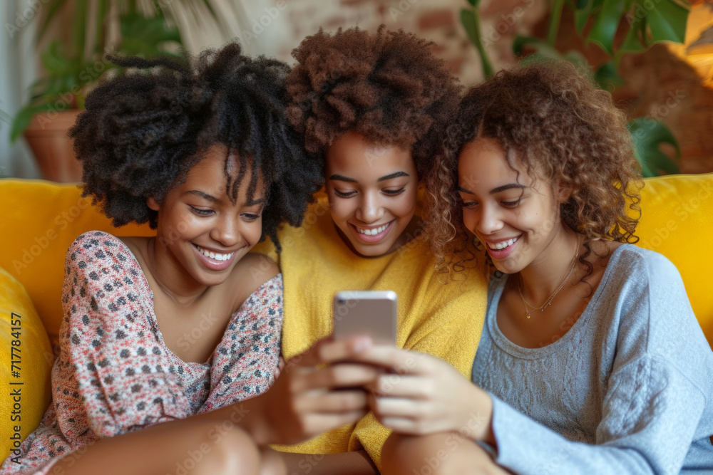 Three afro girls sharing a delightful moment on a yellow couch looking at a smartphone together. Three afro girls sharing a delightful moment on a yellow couch looking at a smartphone together.