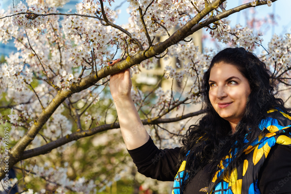 Young woman on the background of blooming cherry trees in the city Young woman on the background of blooming cherry trees in the city