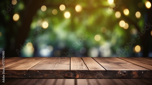 Empty wooden table top with fairy lights hanging on tree in garden at night, bokeh light background