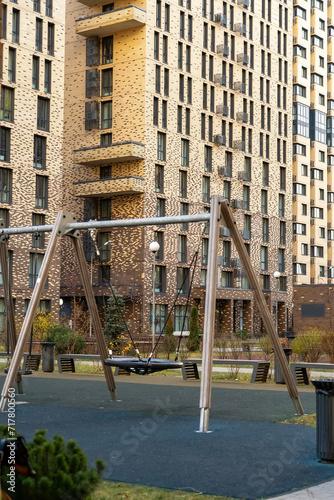 Swing set is located in front of a brick apartment building.