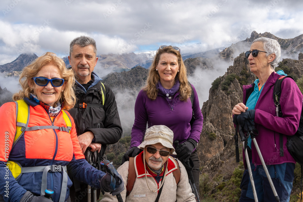 Happy Hiking Group Posing on Mountain with Cloudy Backdrop Happy Hiking Group Posing on Mountain with Cloudy Backdrop