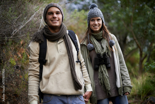 Couple  happy and hiking in forest with holding hands for travel  adventure or wellness and fitness. Man  woman and trekking outdoor in woods for cardio  exercise or workout with smile or backpack