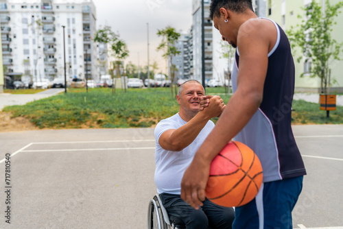 Friends shake hands after friendly free throw games, diversity friendship between a black man and wheelchair bound man