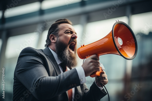 businessman shouting through a megaphone outside in front of office building