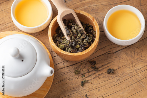 Tea leaves in wood bowl with tea cups on wooden table