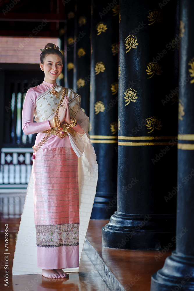 Beautiful girl in traditional Elegant pink dress and yellow sash. Fashion portrait of pretty Asian women in traditional Thai dress. Luxurious dress in Chedi Luang Temple at Chiang Mai, Thailand.
