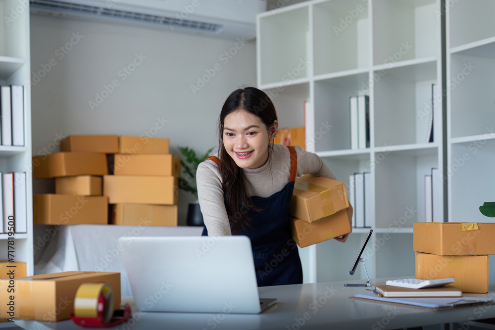 Startup SME small business entrepreneur SME or freelance Asian woman using a laptop with box, Young success Asian woman online marketing package box and delivery concept Startup SME small business entrepreneur SME or freelance Asian woman using a laptop with box, Young success Asian woman online marketing package box and delivery concept