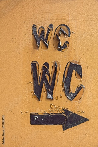 Closeup of wc text and arrow on old cracked wall paint texture background.