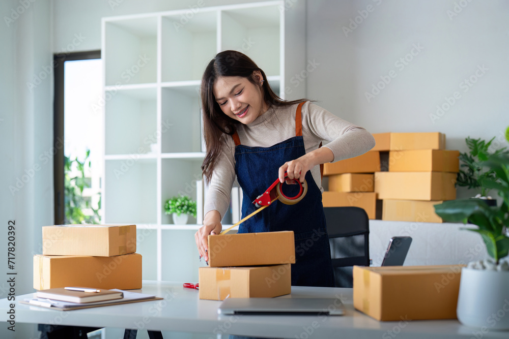 Woman use scotch tape to attach parcel box to prepare goods for the process of packaging, shipping, online sale internet marketing ecommerce concept startup business idea Woman use scotch tape to attach parcel box to prepare goods for the process of packaging, shipping, online sale internet marketing ecommerce concept startup business idea
