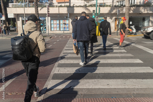 People crossing the pedestrian crossing young boy with a backpack and juggler