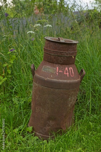 Old and rusty milk jug as a decoration outside in a garden.