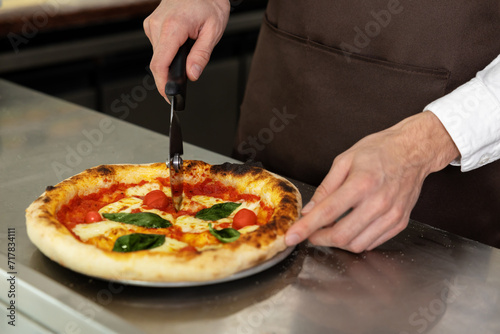 Close up of mans hands cutting pizza