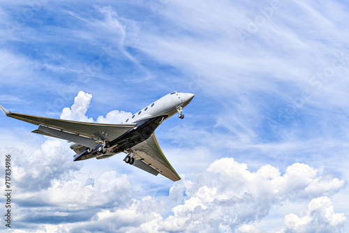 Private business plane flying under blue sky with white clouds