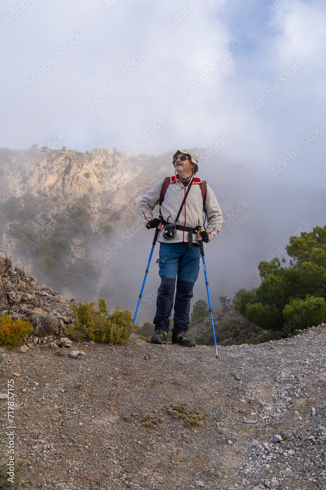 Hiker with Trekking Poles Gazing at Mountainous Fog