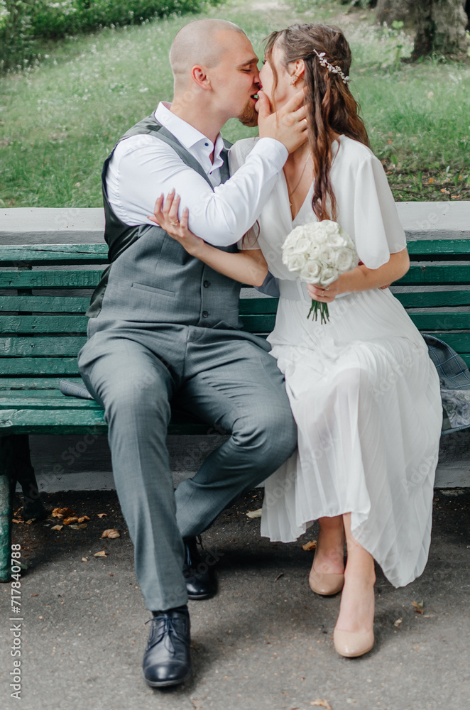 the bride and groom kiss while sitting on a bench the bride and groom kiss while sitting on a bench