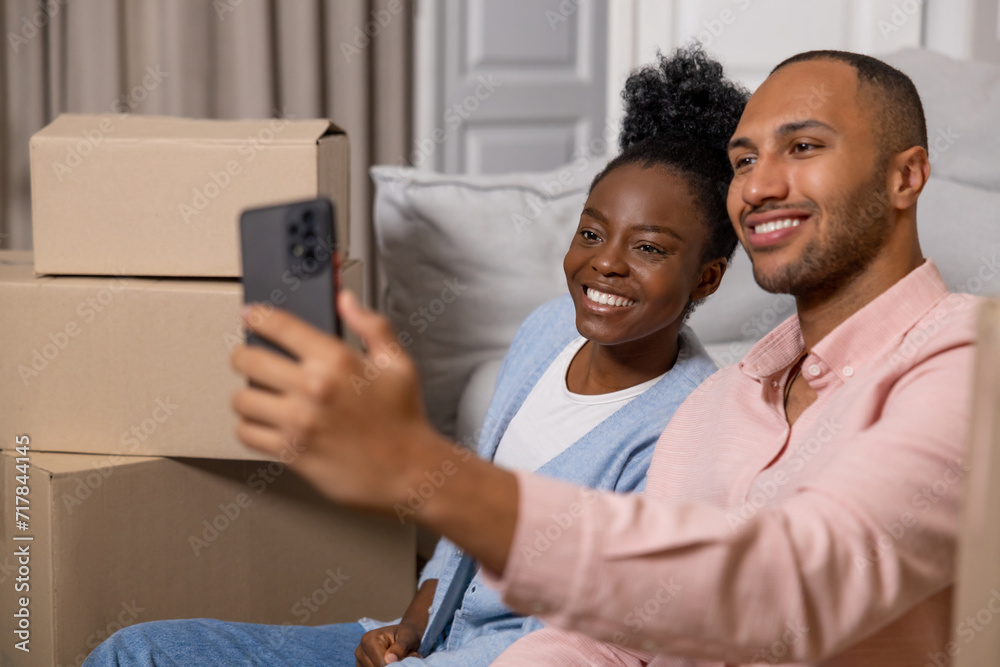 Fototapeta premium Man and woman taking selfie with smartphone in their new home after relocation