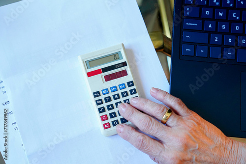 Aerial view of an unrecognizable woman calculating the 2024 tax return with a calculator