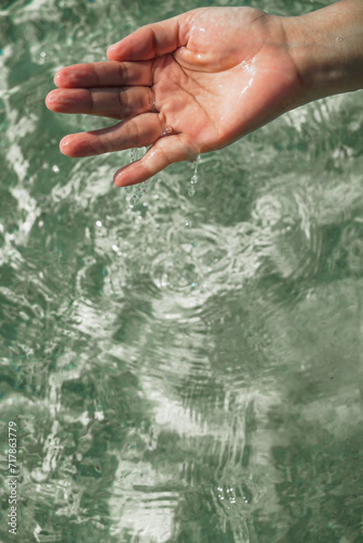 Tender touching surface of ocean water. Woman's hand touching surface of turquoise water in sunlight. Nature water concept, woman hand. Woman's hand at clear turquoise water.